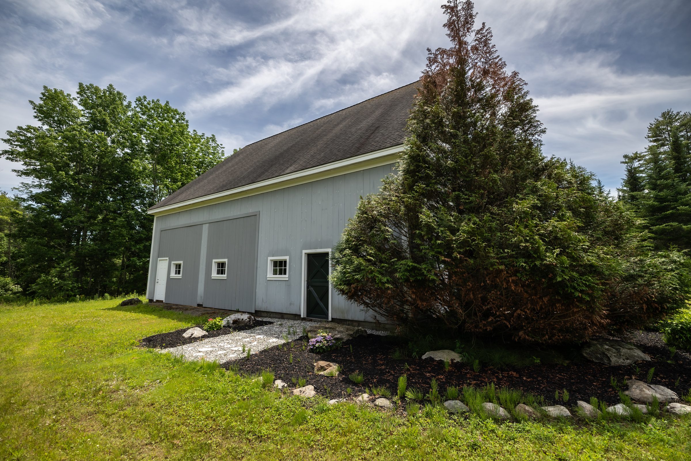 A side angle of the barn showing its full length and shingled roof