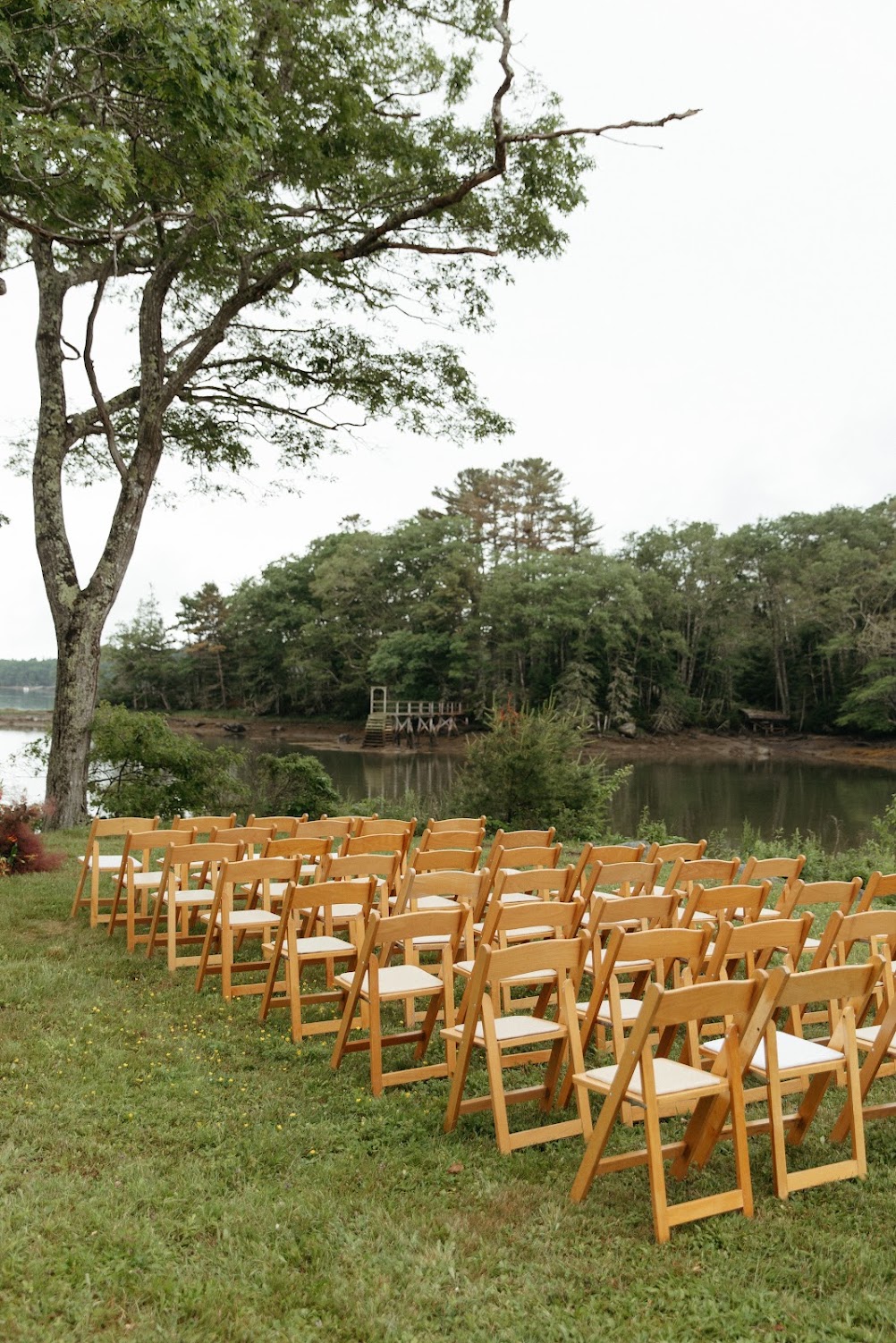 Rows of empty ceremony chairs facing straight down the aisle toward the water