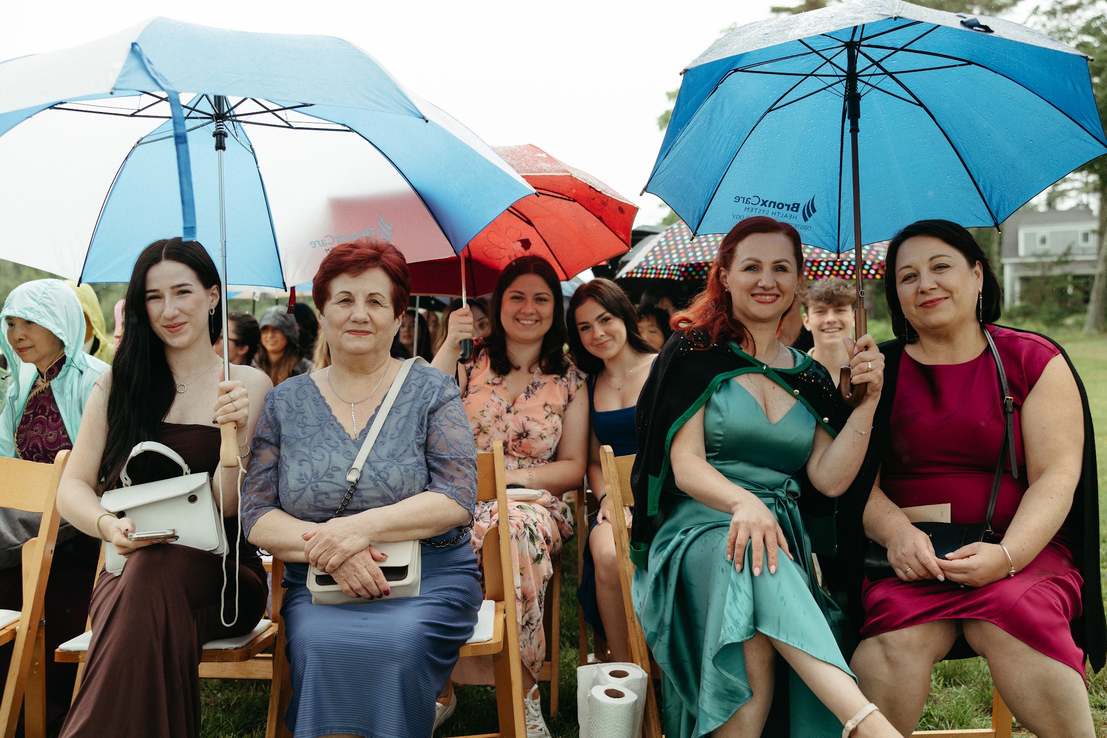 Wedding guests seated under umbrellas during a rainy ceremony