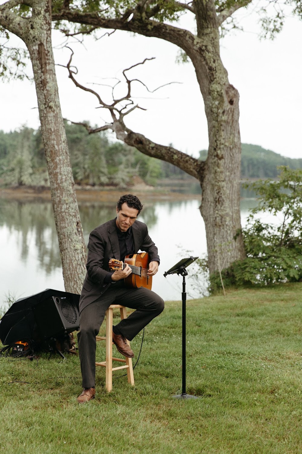 A guitarist plays waterside music during the ceremony beneath the oaks