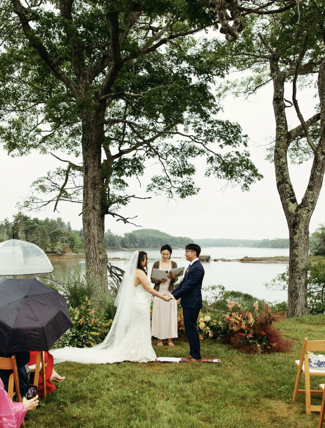 A couple holds hands during their ceremony with the harbor visible behind them