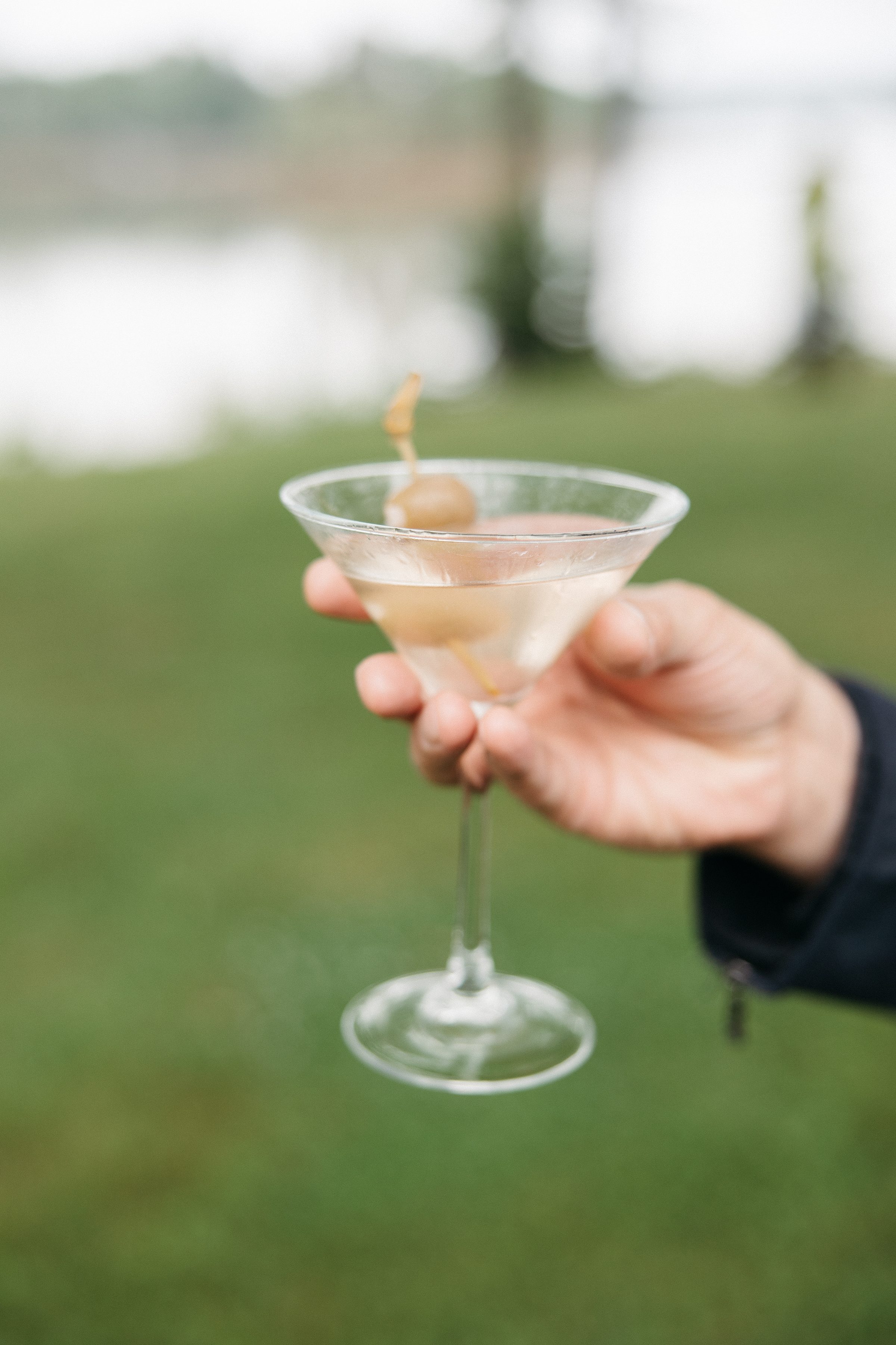A guest holds a martini with the harbor blurred in the background
