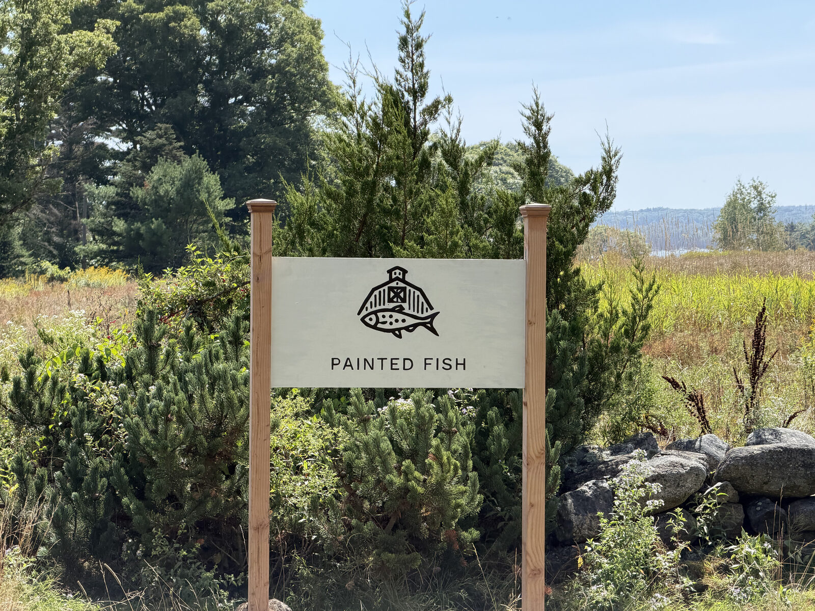 The Painted Fish entrance sign at the edge of the meadow