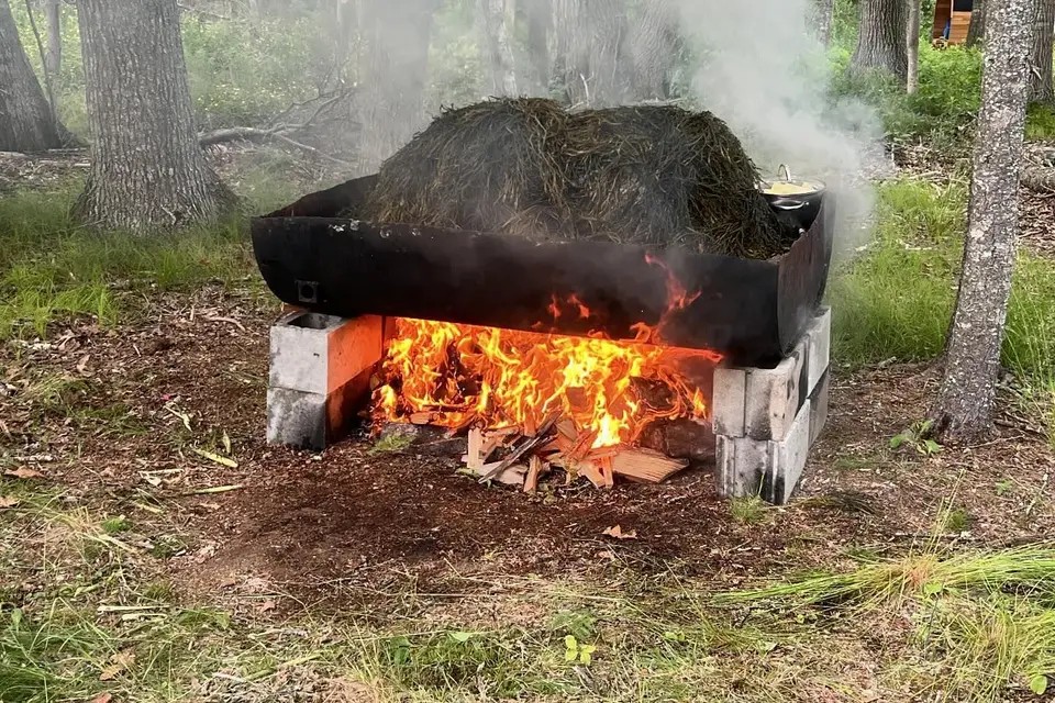 A traditional Maine clambake fire pit, seaweed steaming over an open wood fire