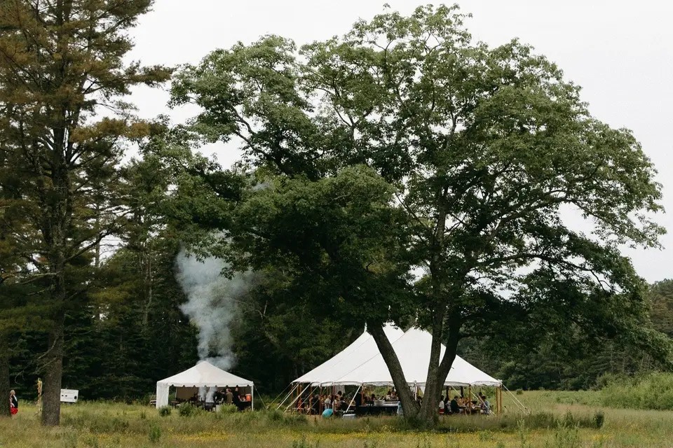 The reception tent and a smaller catering tent pitched in the field beneath a large oak tree