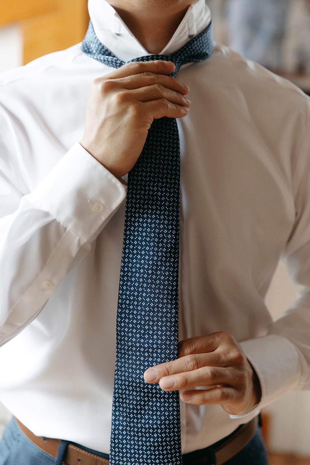 A groom ties his tie while getting ready