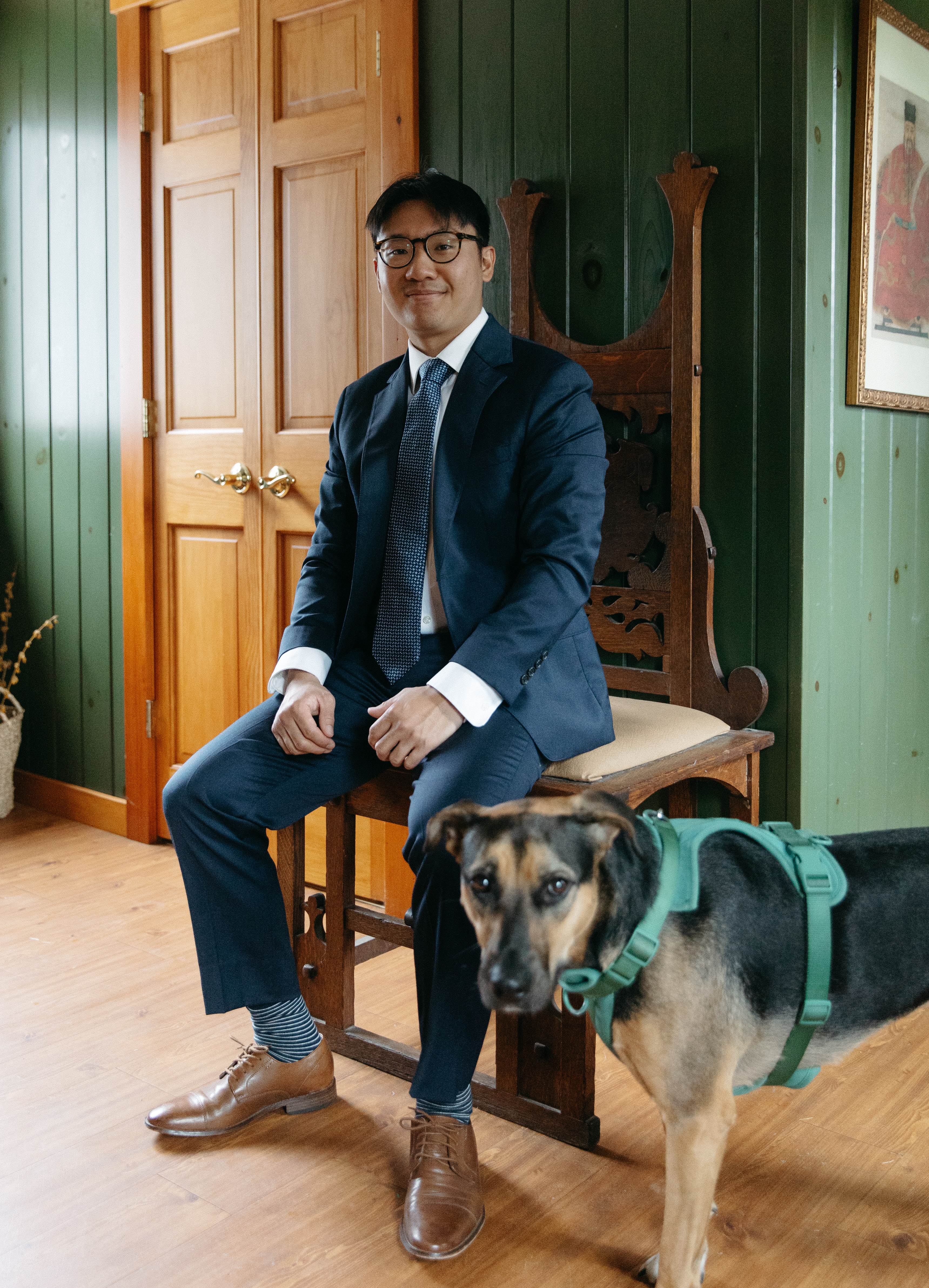 A groomsman getting ready, with the couple's dog checking in beside him