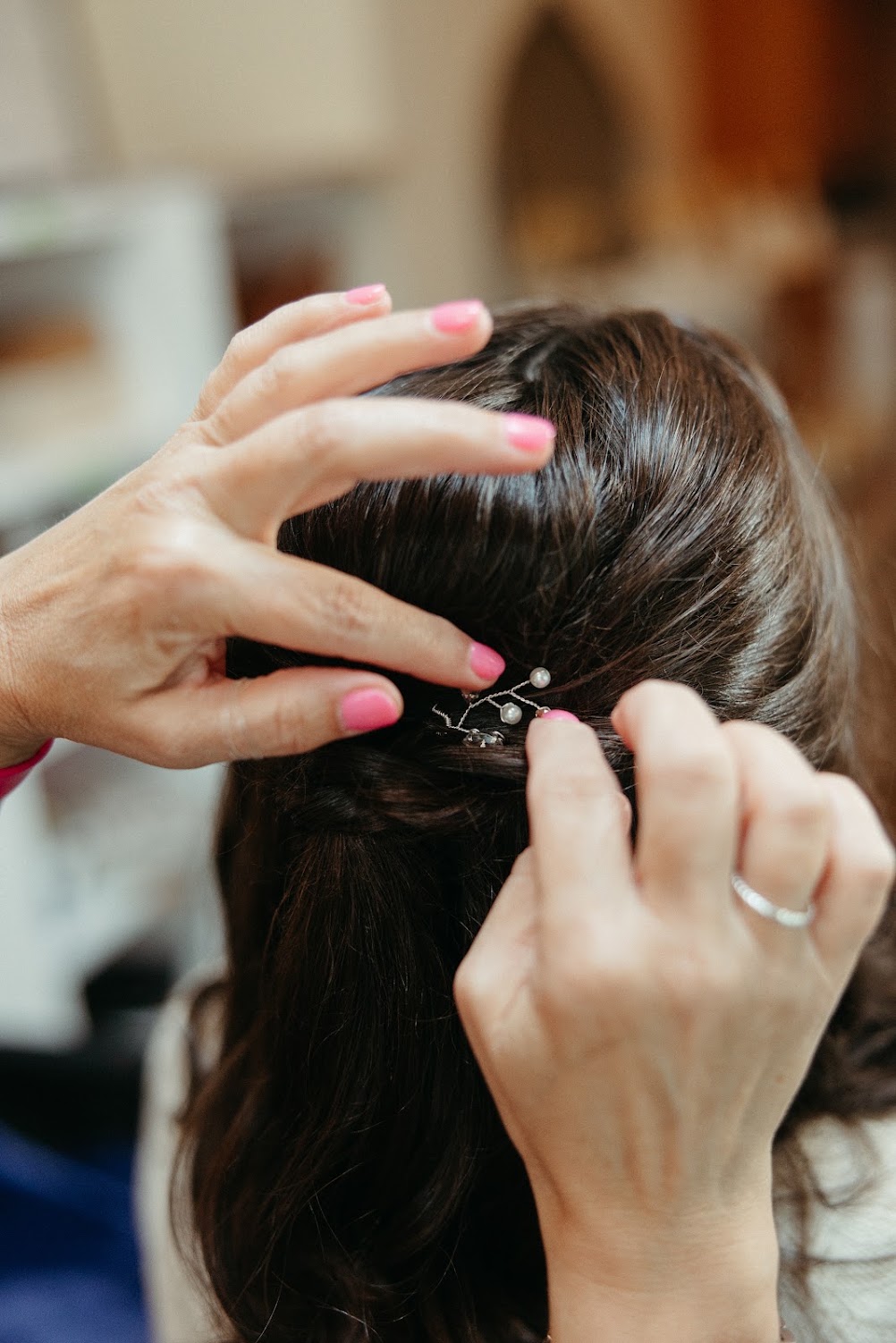 Close-up of a hairstylist pinning a pearl hairpiece into a bride's hair