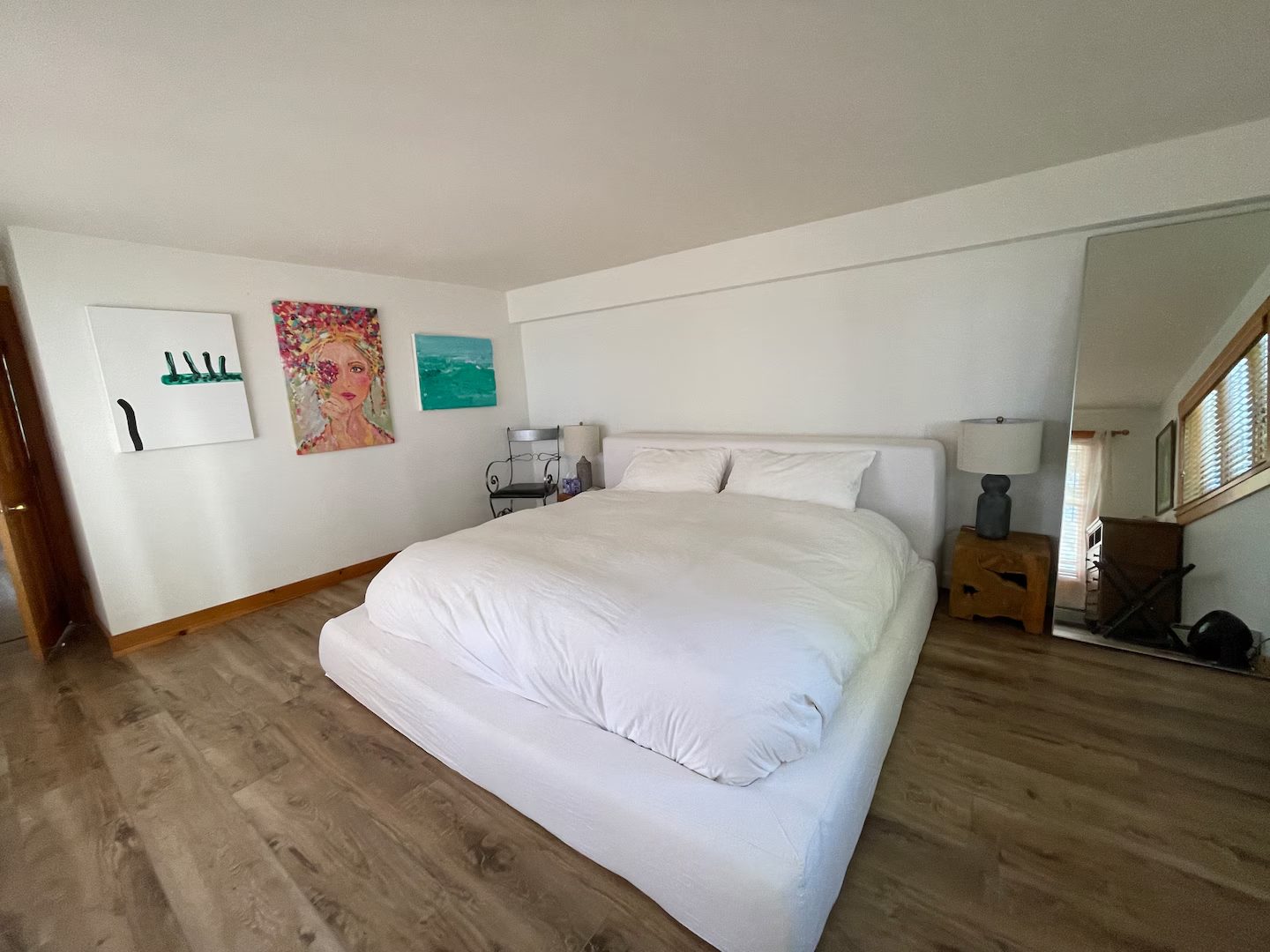 A bright bedroom hung with original paintings from the property's artist-residency days