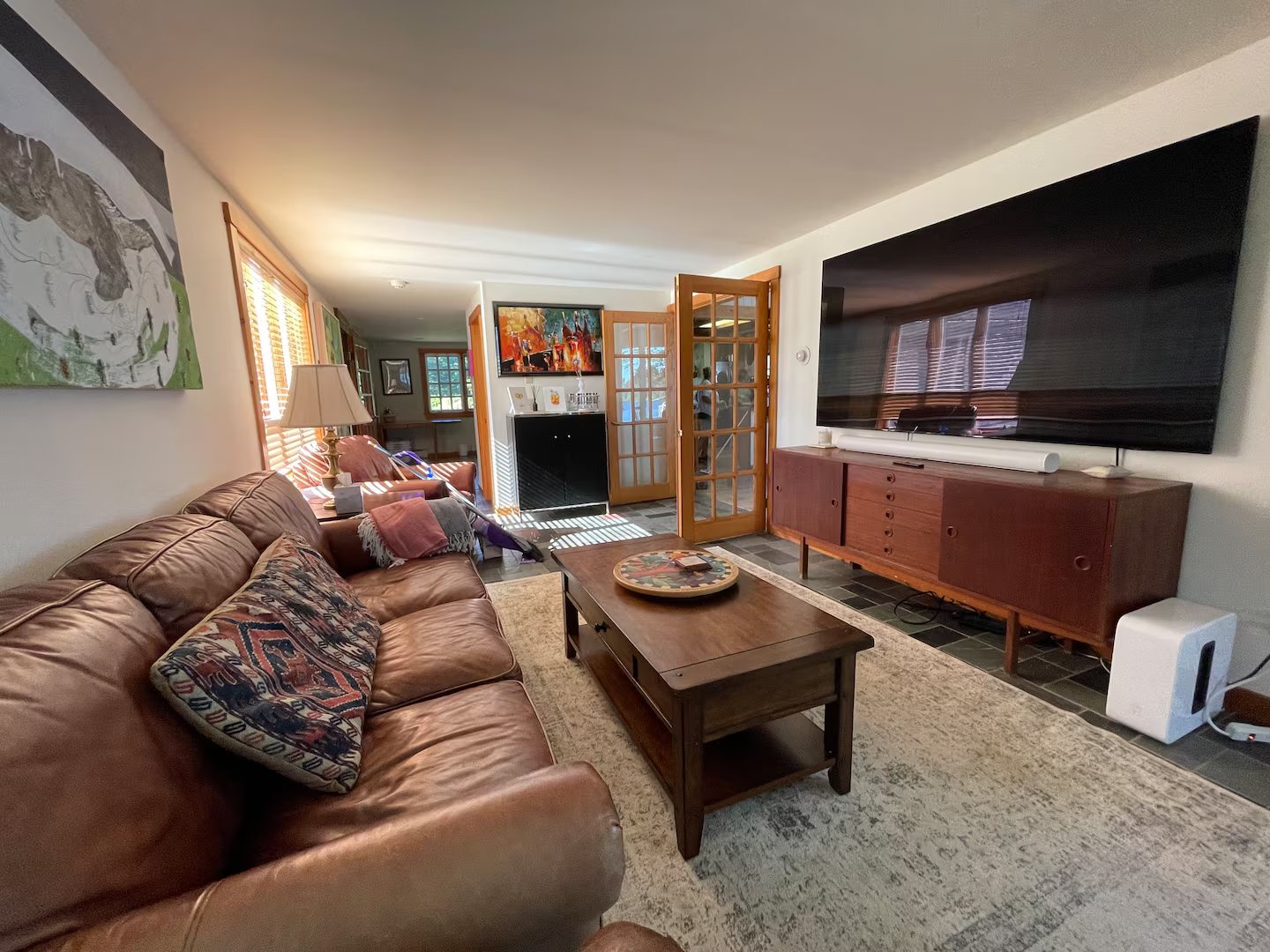 A cozy den with a leather sectional and original art on the walls