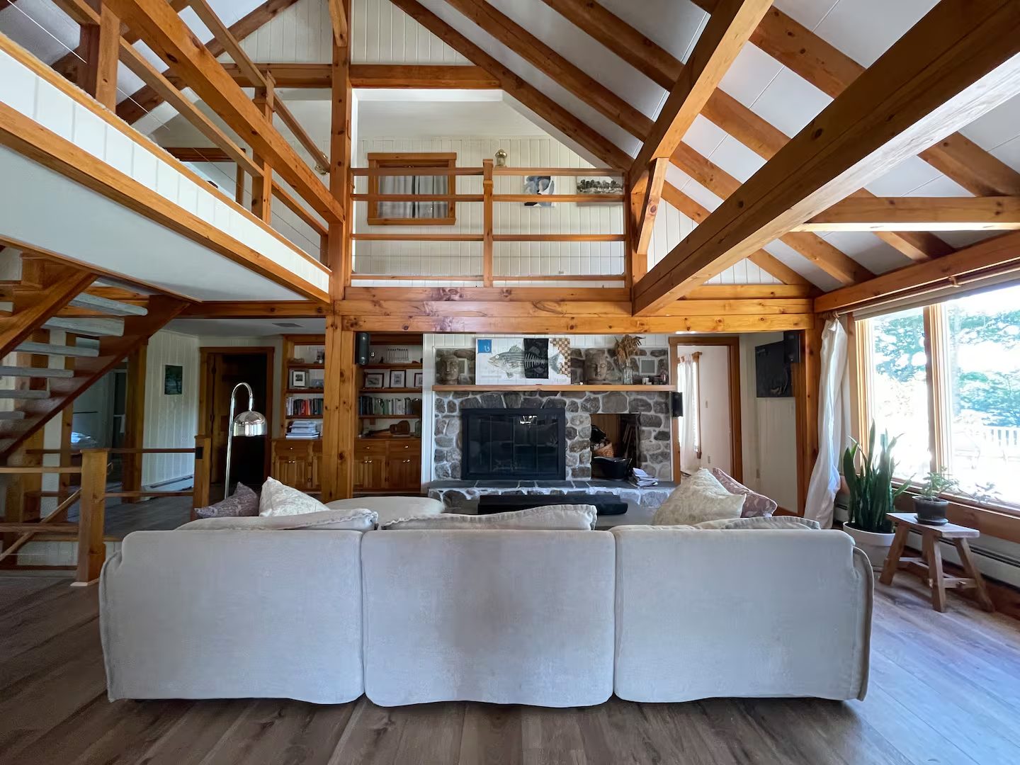 The great room, with exposed post-and-beam construction, a stone fireplace, and a cozy sectional sofa