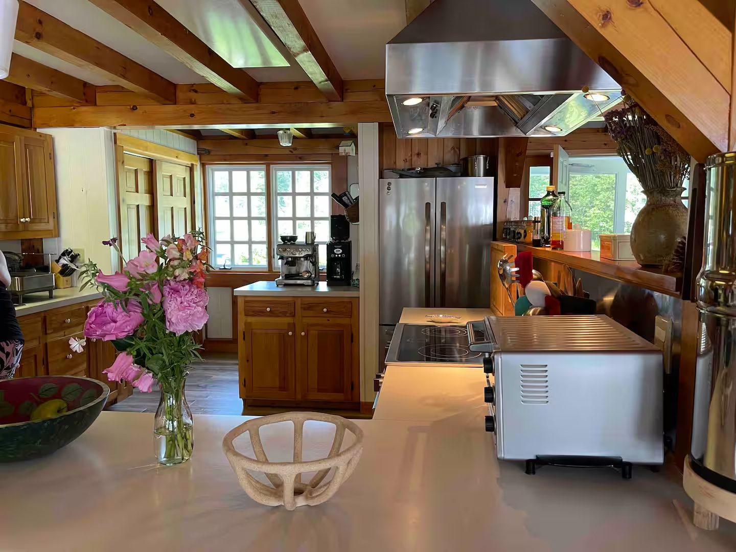 The kitchen, with wood cabinetry, stainless appliances, and fresh peonies on the counter