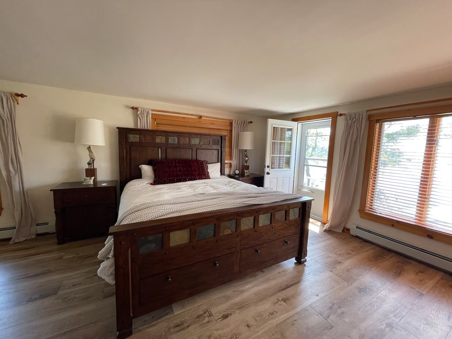 The primary suite, with a wood bed frame and a private door out to the deck