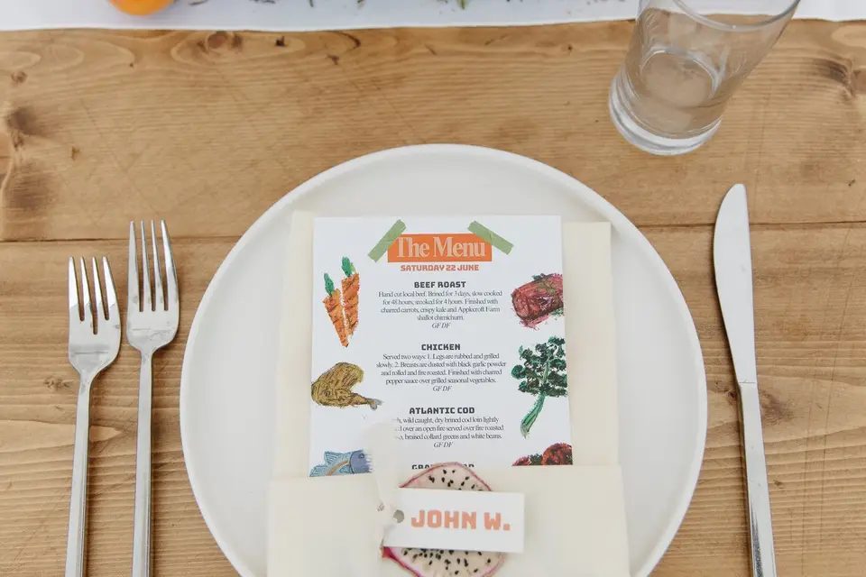 A hand-illustrated dinner menu card at a table setting